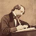 Charles Dickens writing with a quill pen.